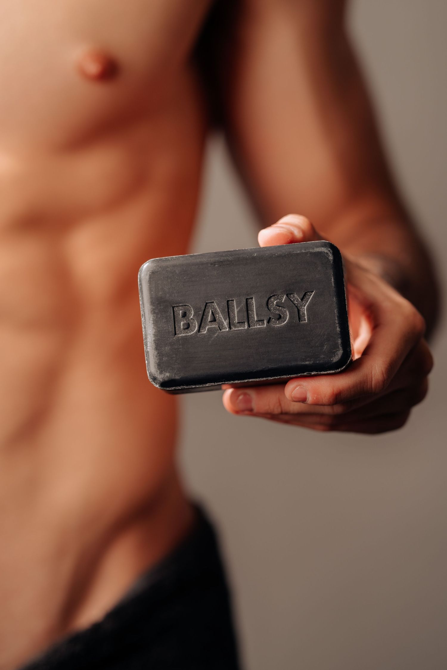 Close up of a black soap bar with embossed Ballsy text.