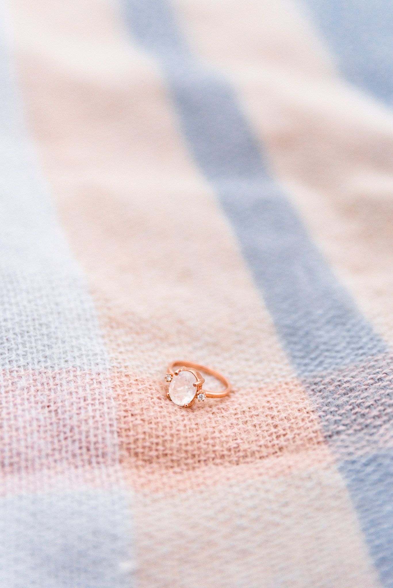 moonstone and rose gold engagement ring on pink and light blue blanket