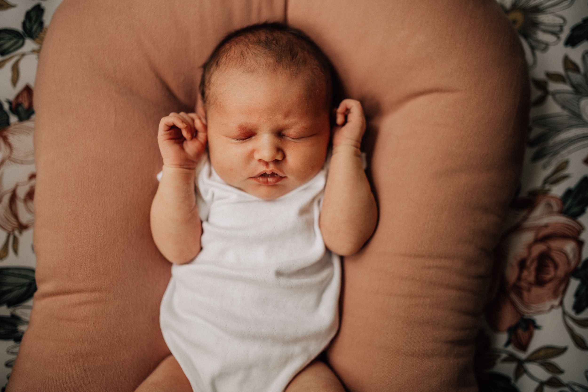 baby in a boppy and white Carters onesie