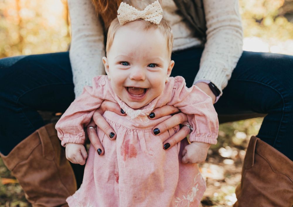 baby girl smiling in her moms hands