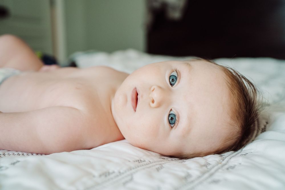 baby laying on the bed staring into the camera