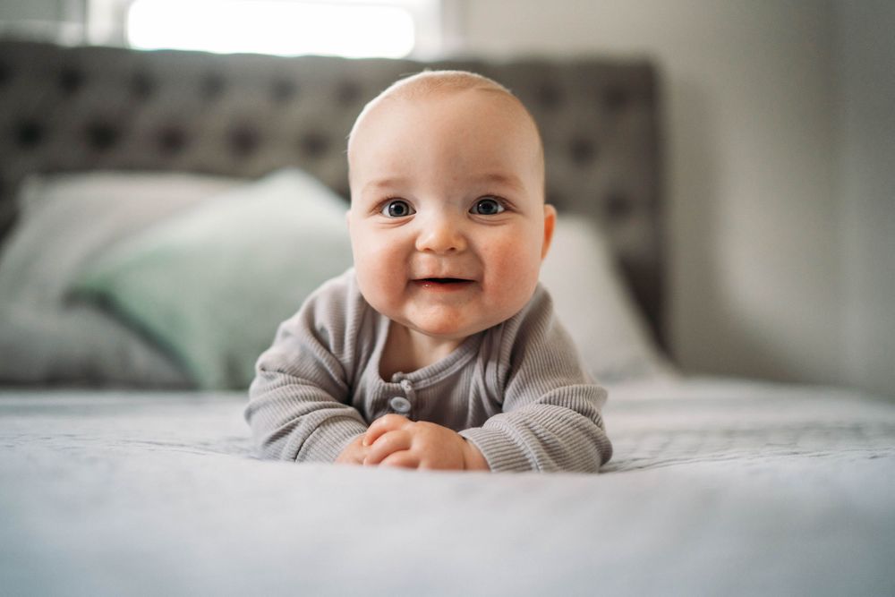baby laying on a bed smiling