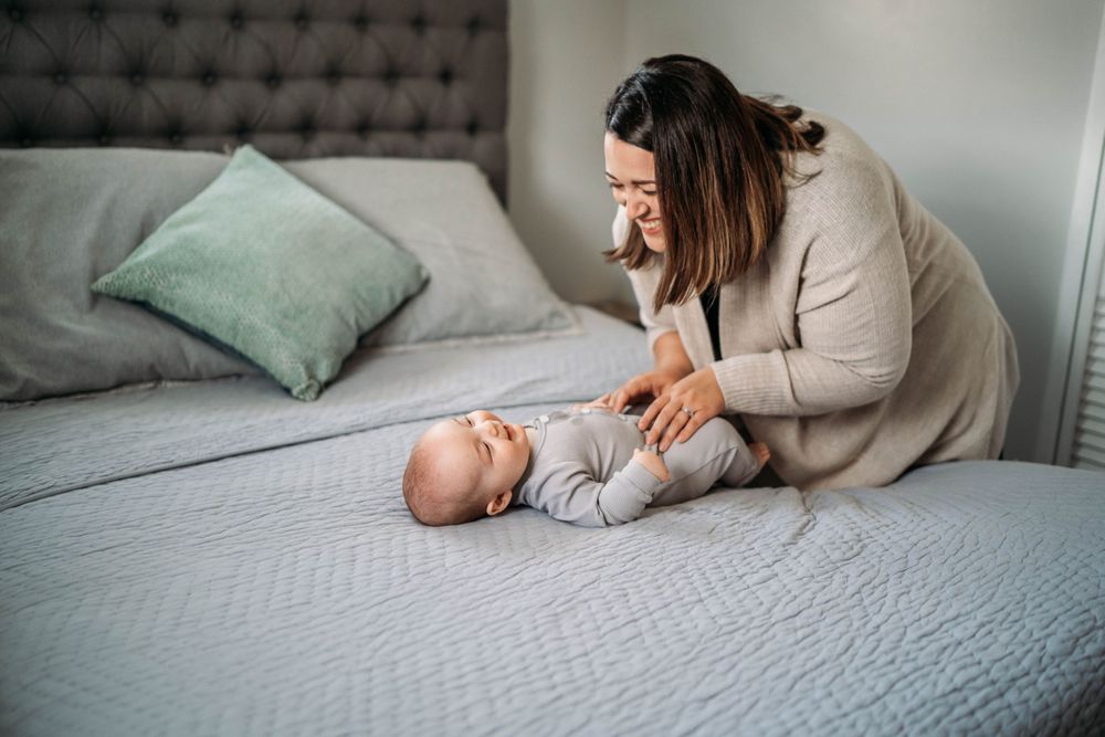 a mom tickling her baby on her bed of her boston home