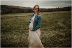 Blonde pregnant mom in field smiling at camera