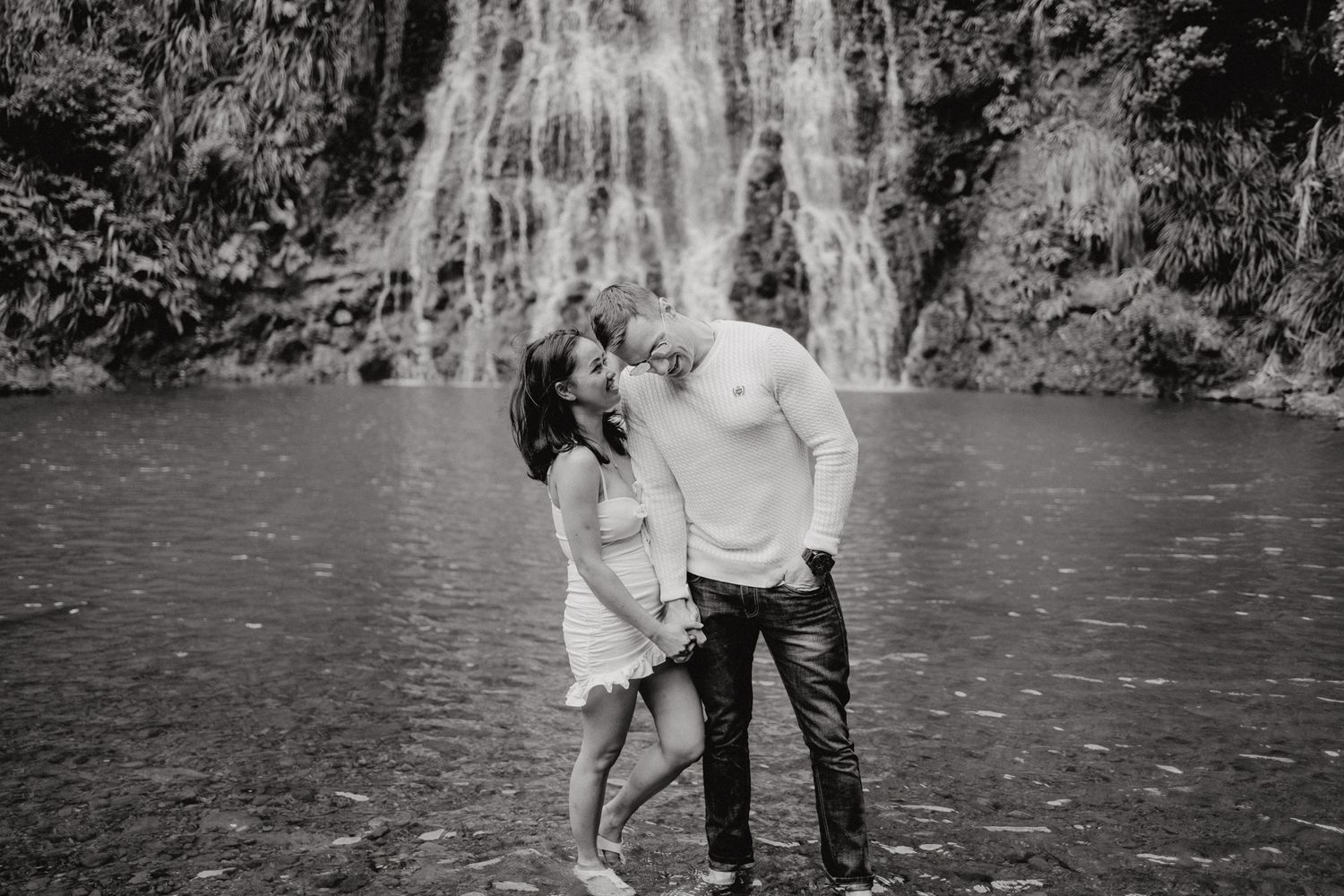 A couple talking in Karekare Falls for their post-wedding photoshoot with Apertured Media-Auckland Wedding Photographer.