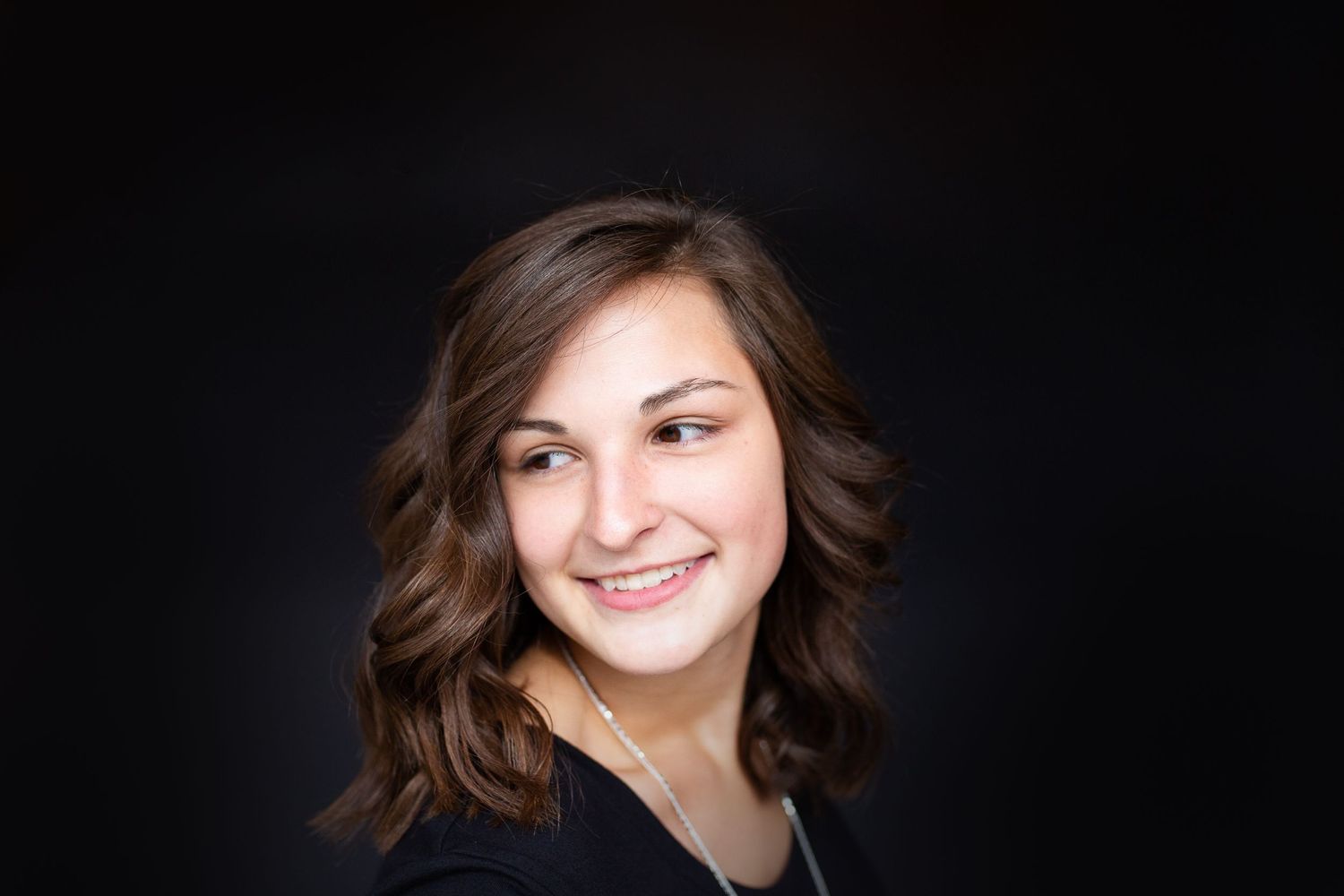 senior girl with brown hair looking over shoulder