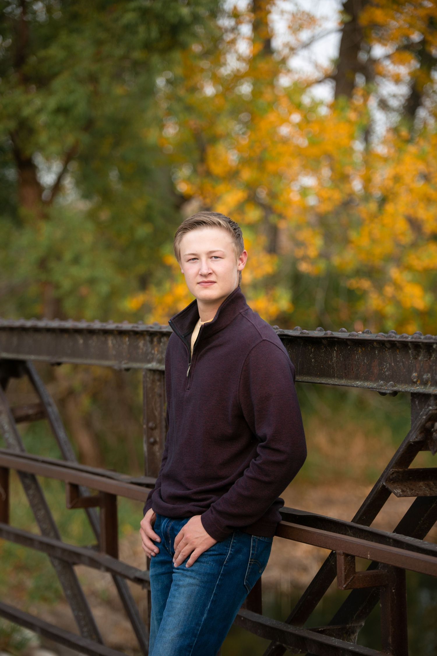 high school boy on industrial bridge with fall foliage
