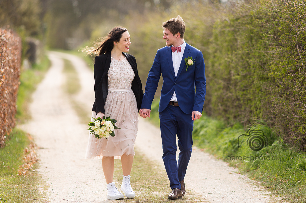 Happy wedding couple along a path on a sunny spring day.