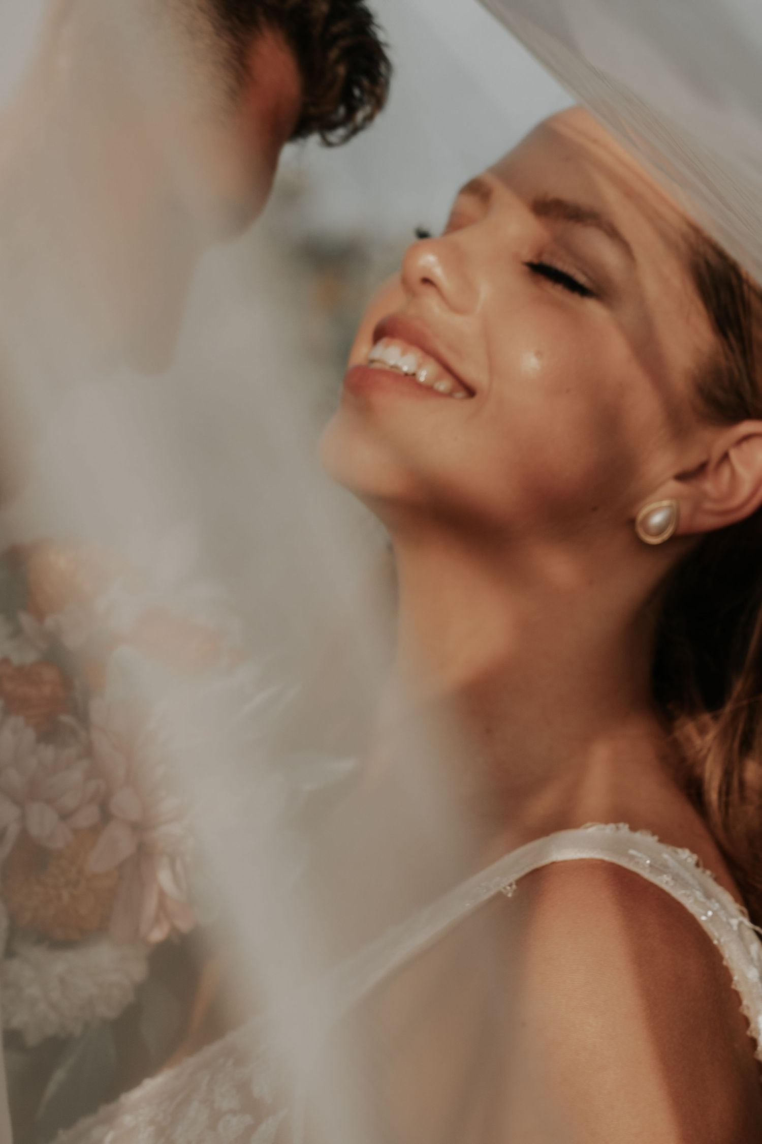 Close-up of joyful expression through delicate white veil at wedding celebration.