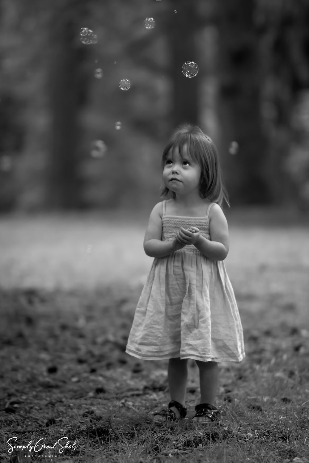 A little girl looking up at bubbles.