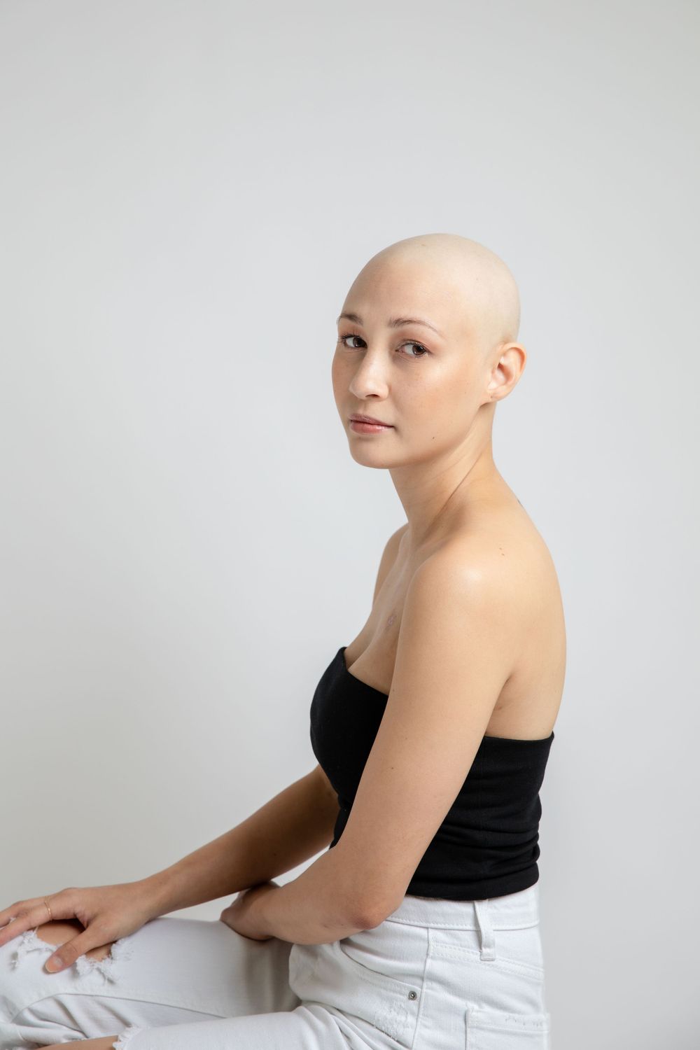 Side profile portrait of person in black top against minimalist white background.