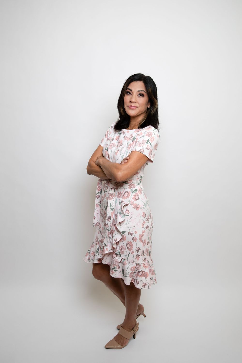 Full length portrait of person in floral dress posing against white background.