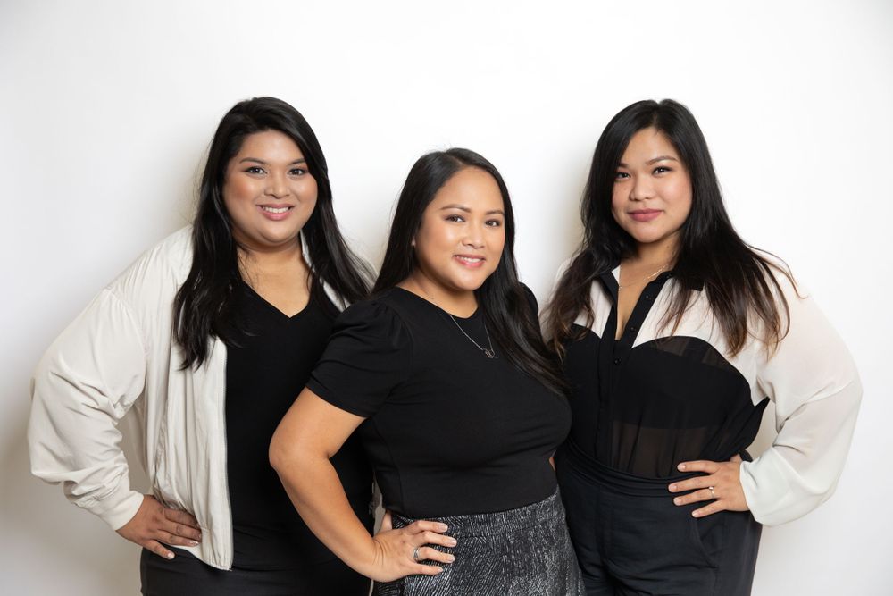 Professional group studio portrait of three people in coordinated black and white outfits.