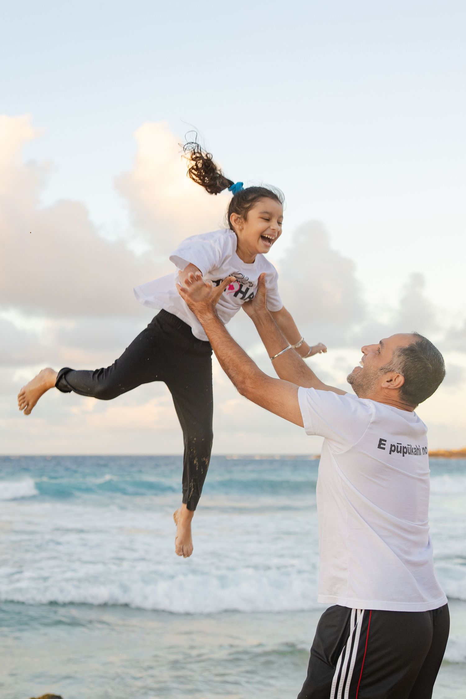 Maui's most affordable photographer - dad throws daughter in the air as she laughs on beaches of lahaina
