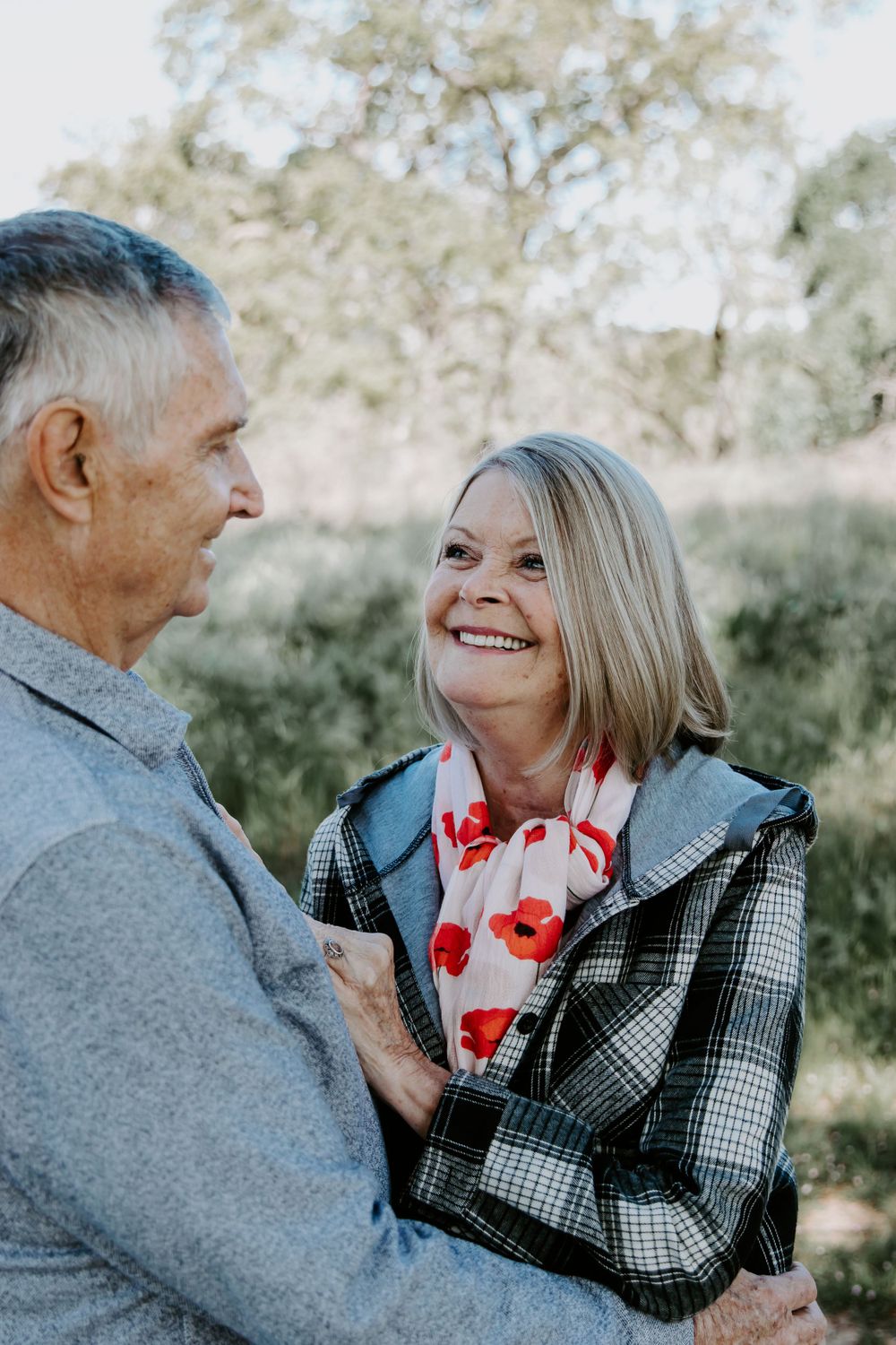 A couple sharing a tender moment outdoors wearing casual winter clothing with a floral scarf.