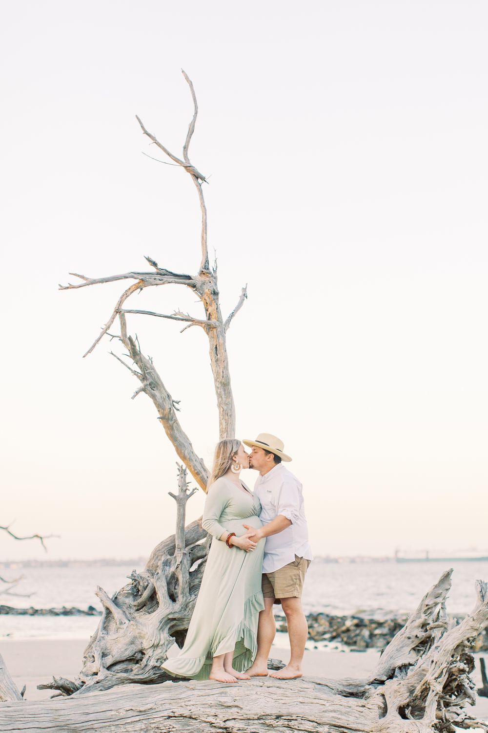 kayley and josh taking their maternity session photos at driftwood beach on jekyll island, ga