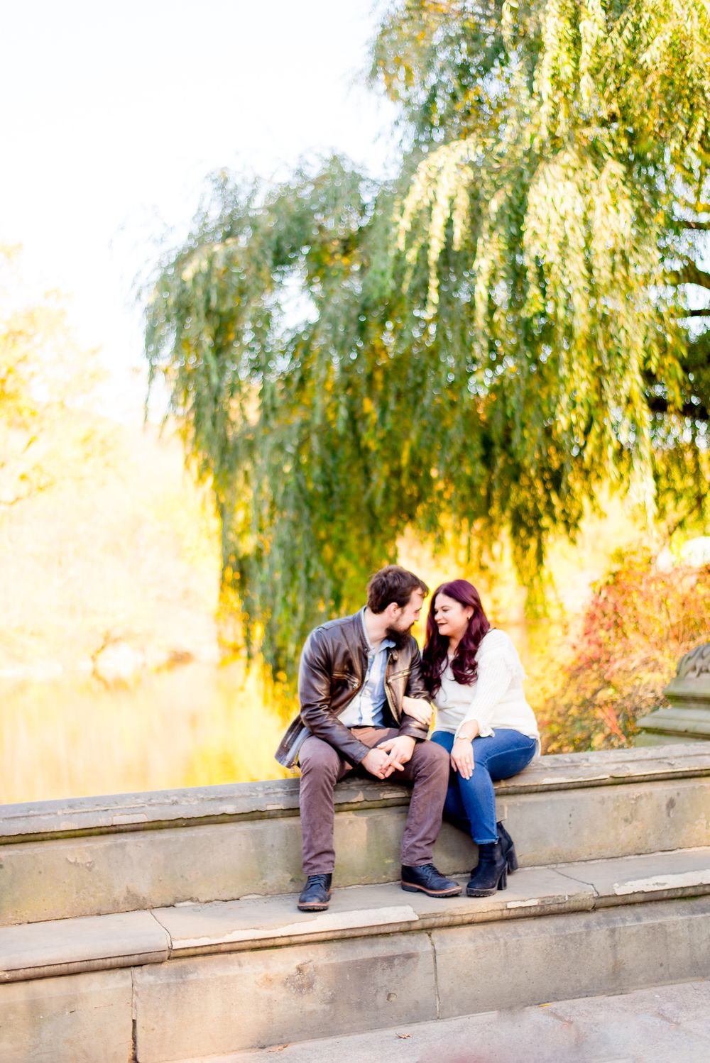 engaged man and woman sitting by the pond at Central Park for fall engagement pictures
