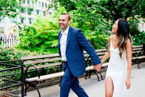 engaged couple holding hands walking through Flatiron District NYC laughing
