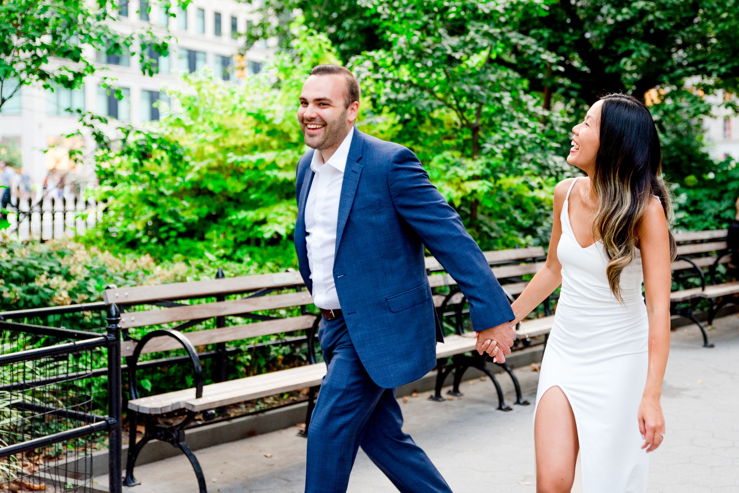 engaged couple holding hands walking through Flatiron District NYC laughing