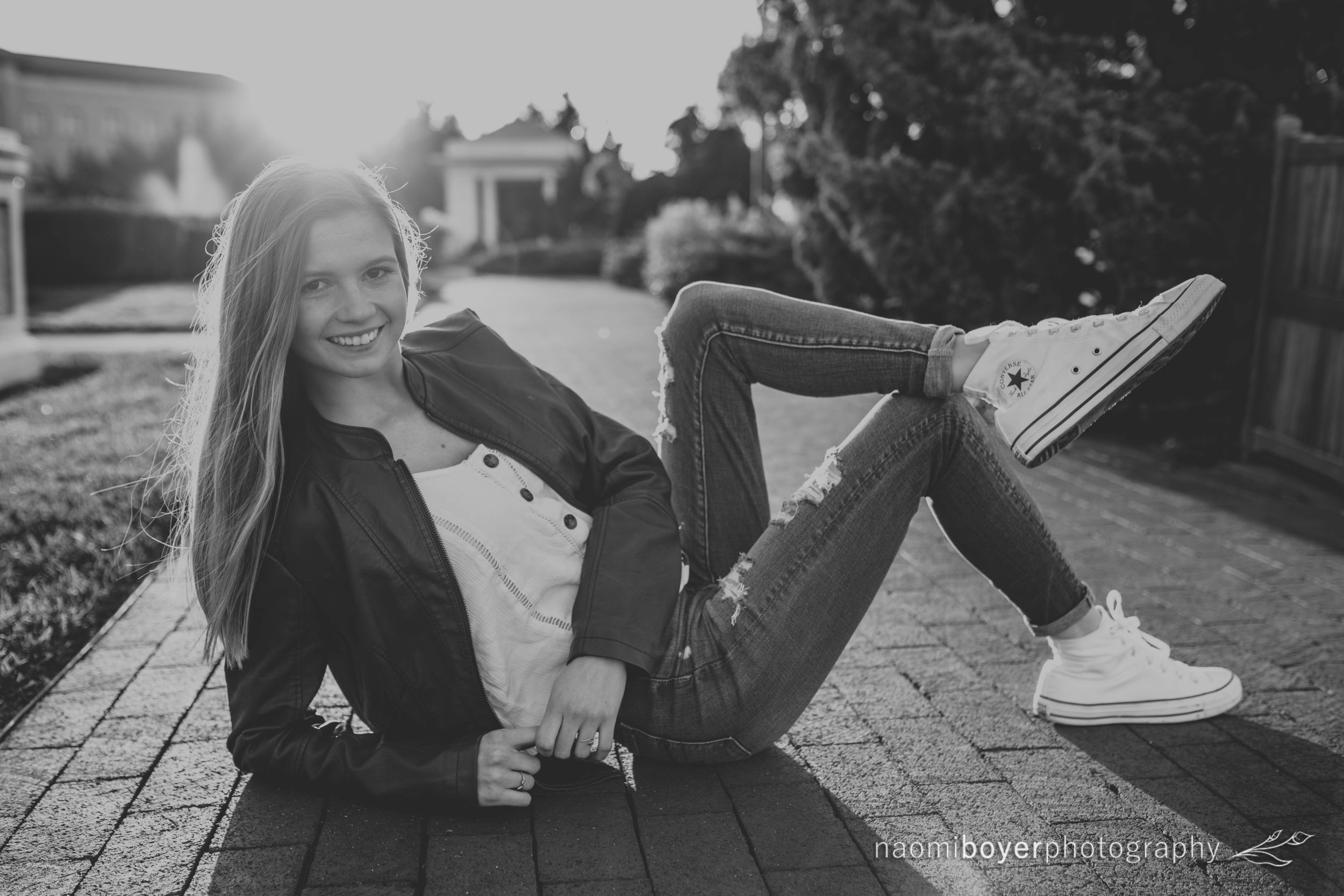 Young lady with white converse shoes relaxes on walkway outside