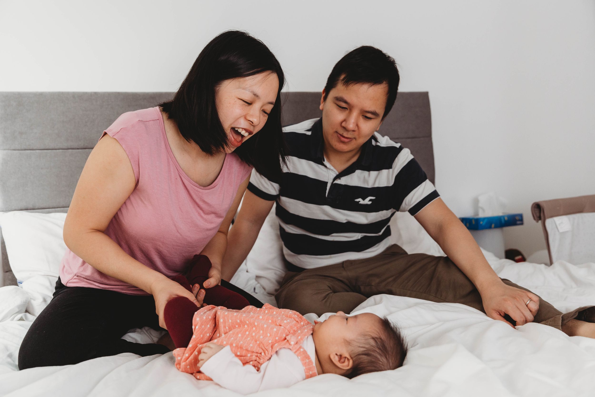 asian family mum dad baby girl cuddling on bed