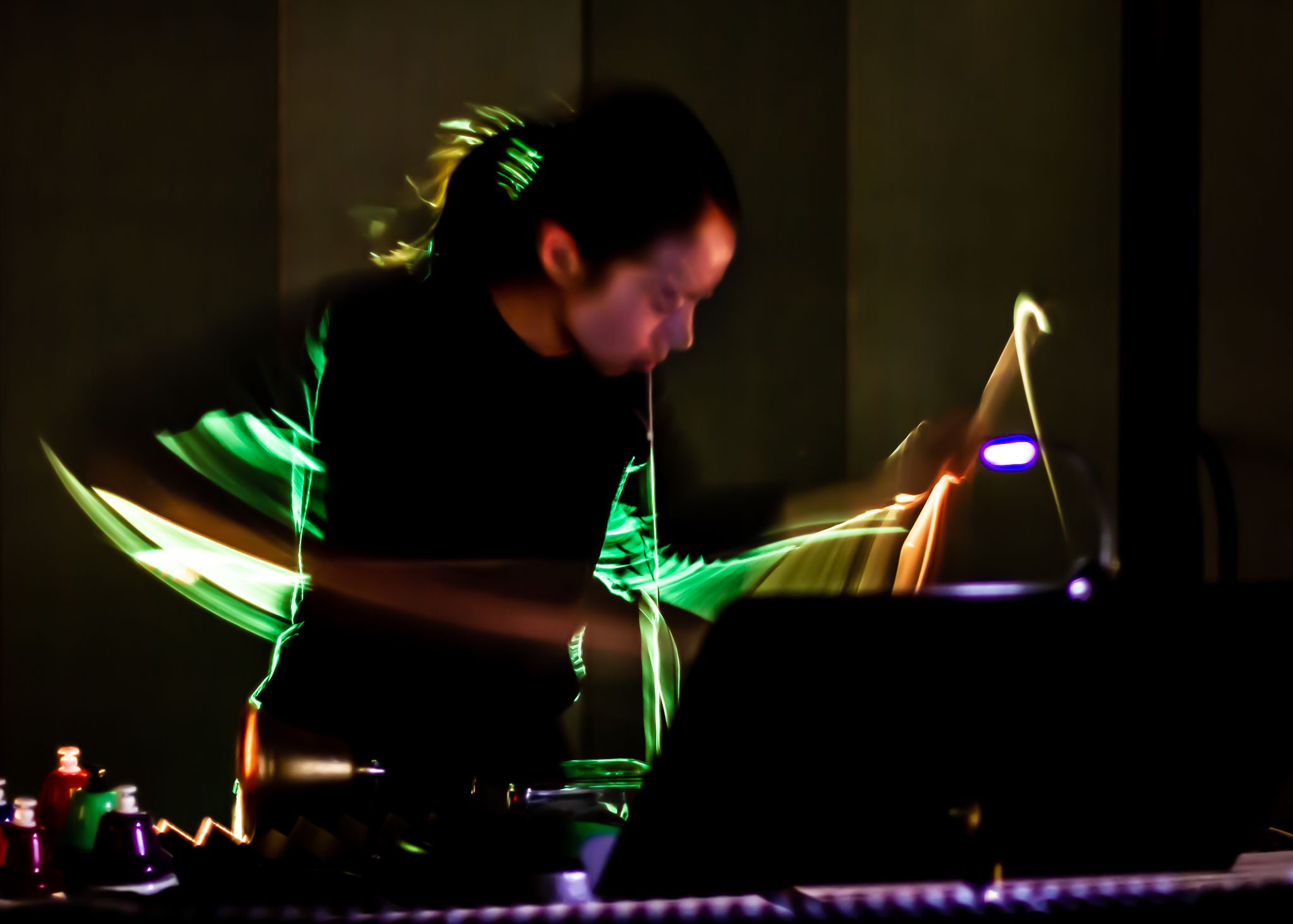 Percussionist Rebekah Ko is surrounded by swoops of light in an otherwise dark room.