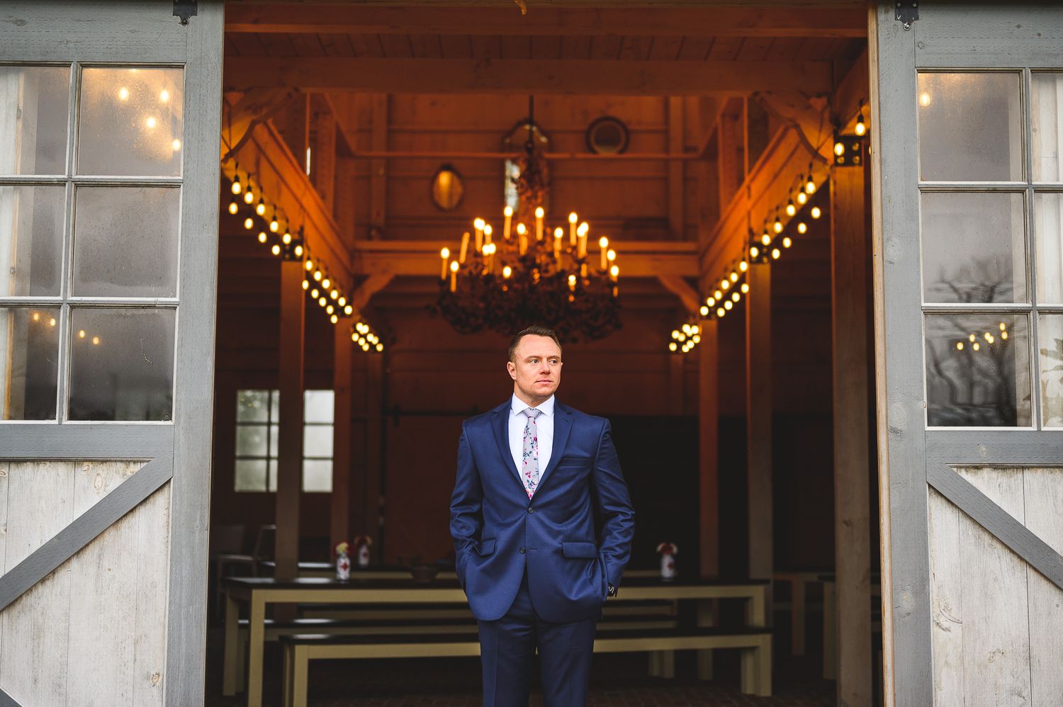 groomsman portrait in front of rustic barn doors at Edel Haus alpaca farm