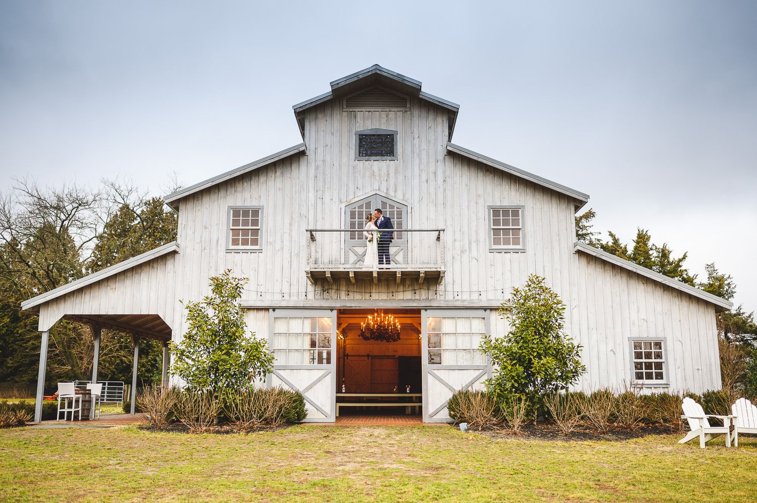 bride and groom kissing outside barn door deck at Edel Haus alpaca farm
