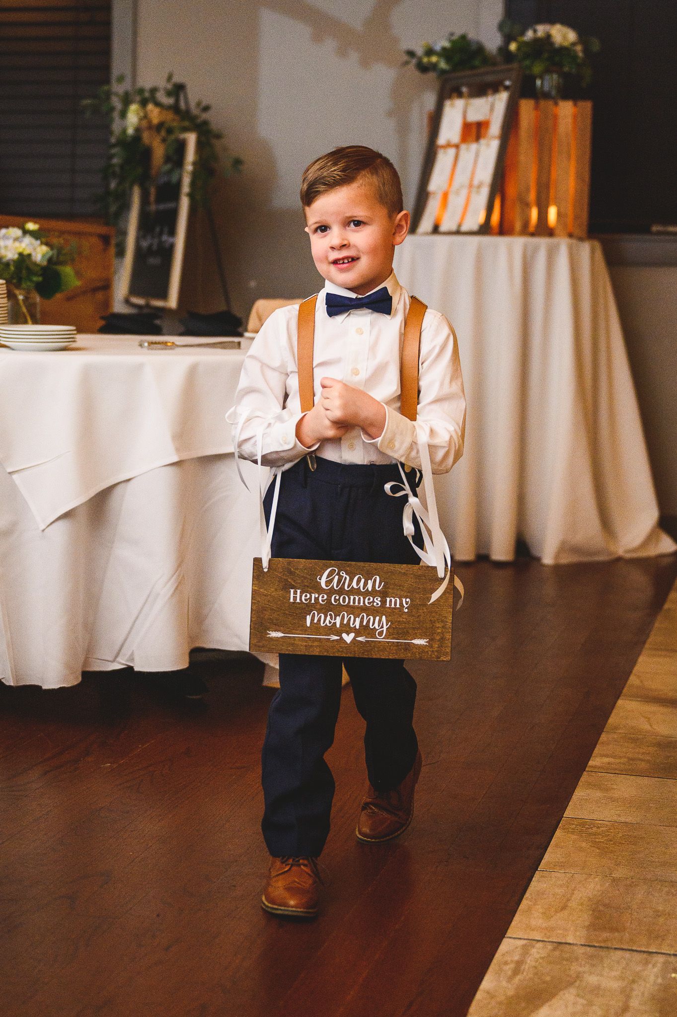 ring bearer walking down with sign during wedding ceremony