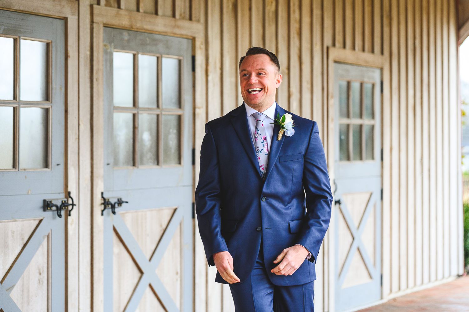 groom smiling in blue suit during the first look