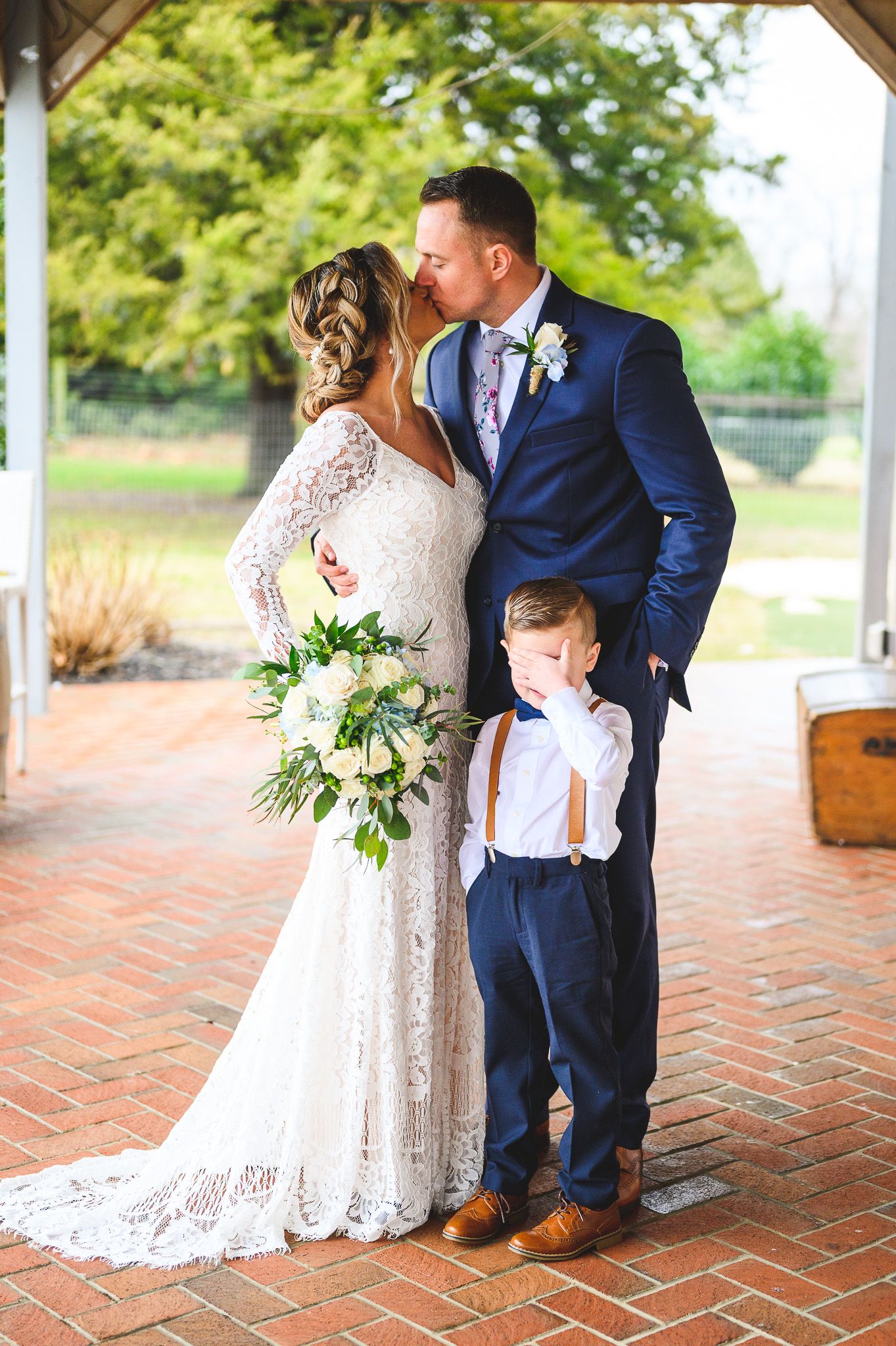 bride and groom kissing with son holding hand over face at Edel Haus alpaca farm