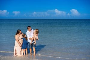 Family of 4 with mom and dad and two daughters standing in the ocean