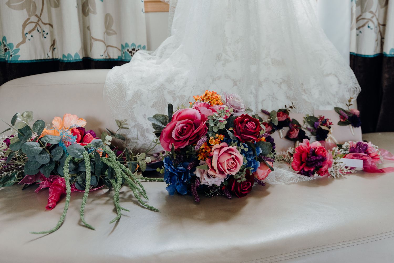 Elegant floral arrangement with pink and burgundy flowers alongside a white wedding veil.
