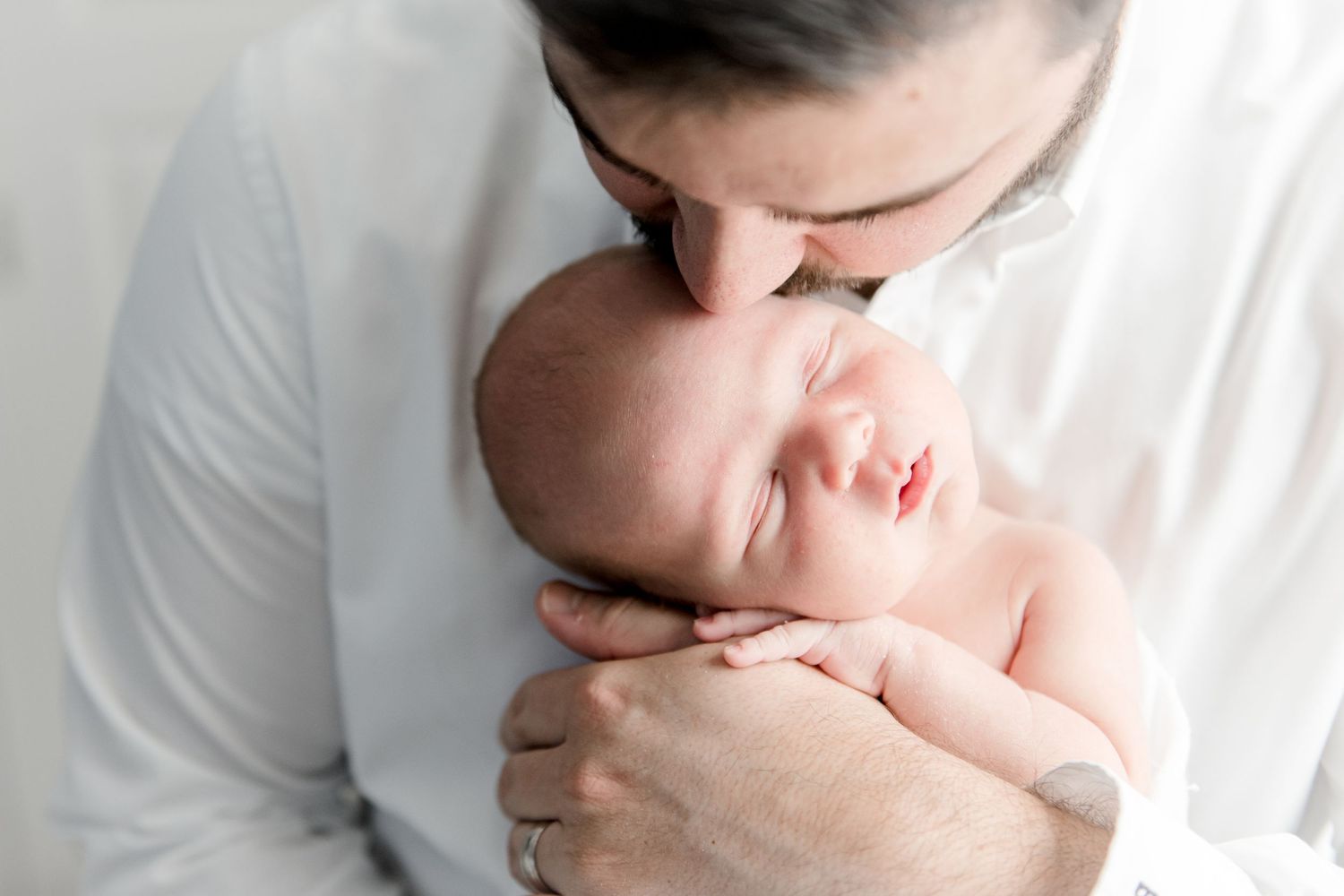 Father kisses newborn son's head while he sleeps
