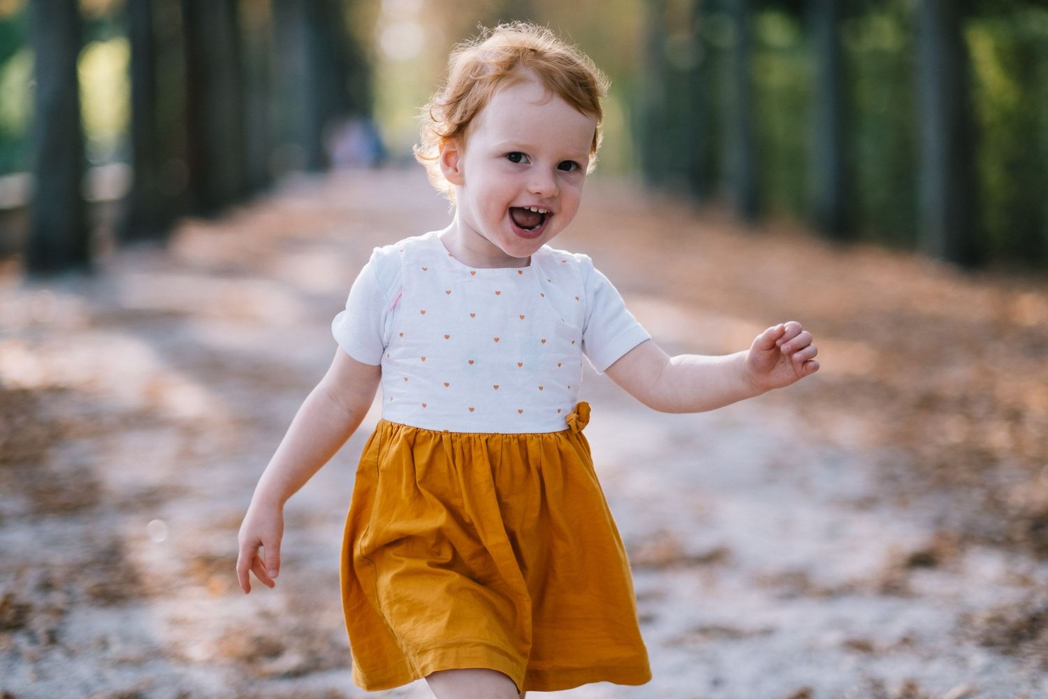 Mädchen mit orangefarbenem Kleid rennt durch Schwetzinger Schlossgarten