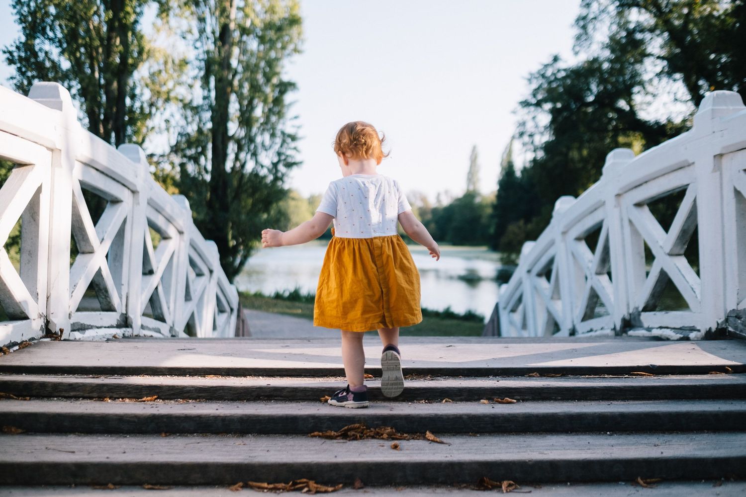 Mädchen mit orangefarbenem Kleid läuft über Brücke im Schwetzingen Schlossgarten