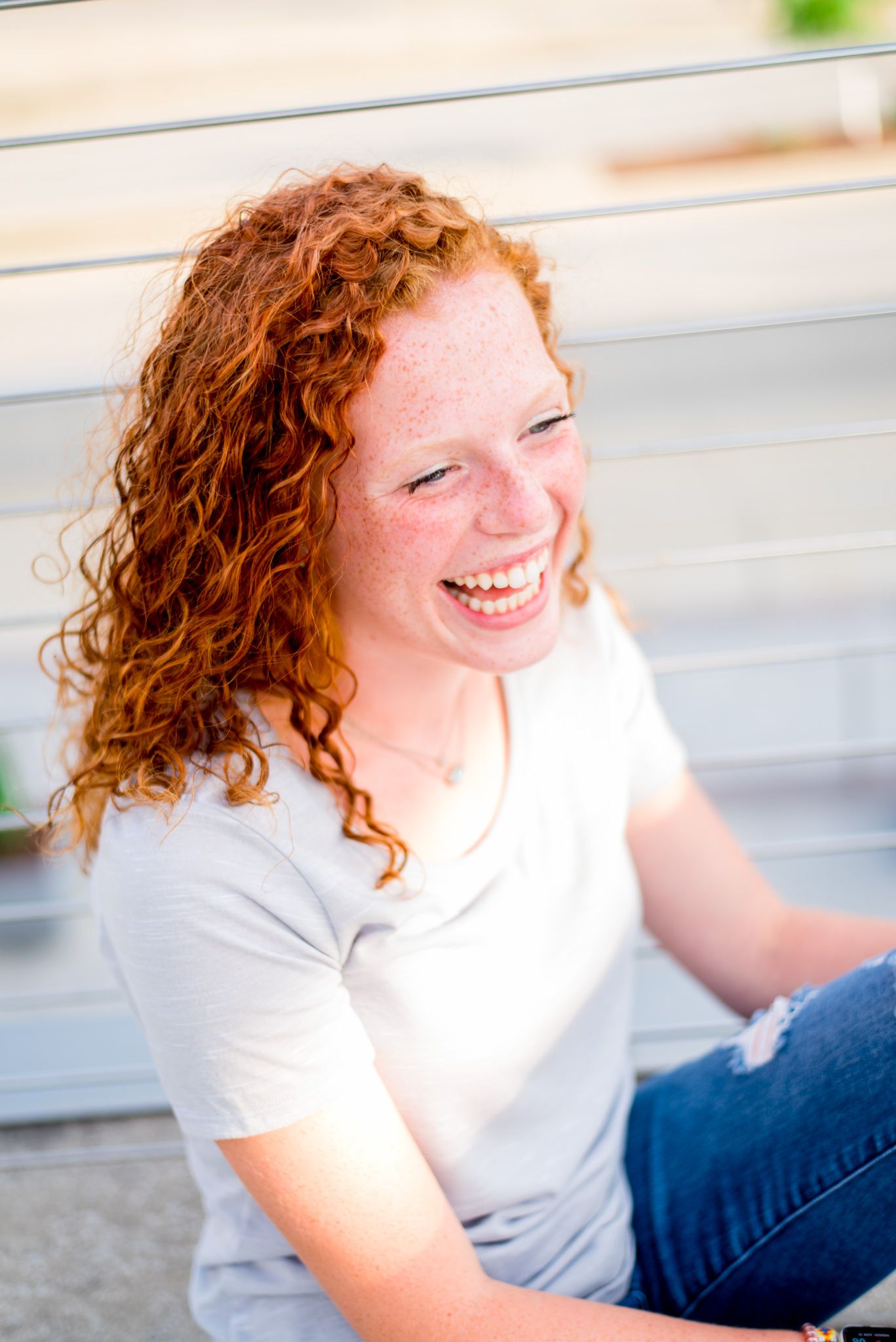 redhead girl in grey shirt laughing next to wire fence in Smale Park
