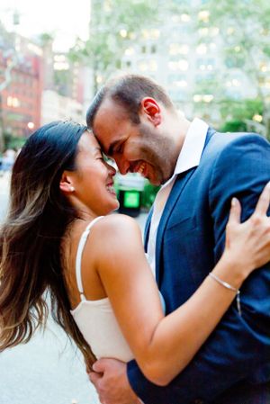 man and woman laughing with foreheads together in front of building at dusk in Madison Square Park NYC