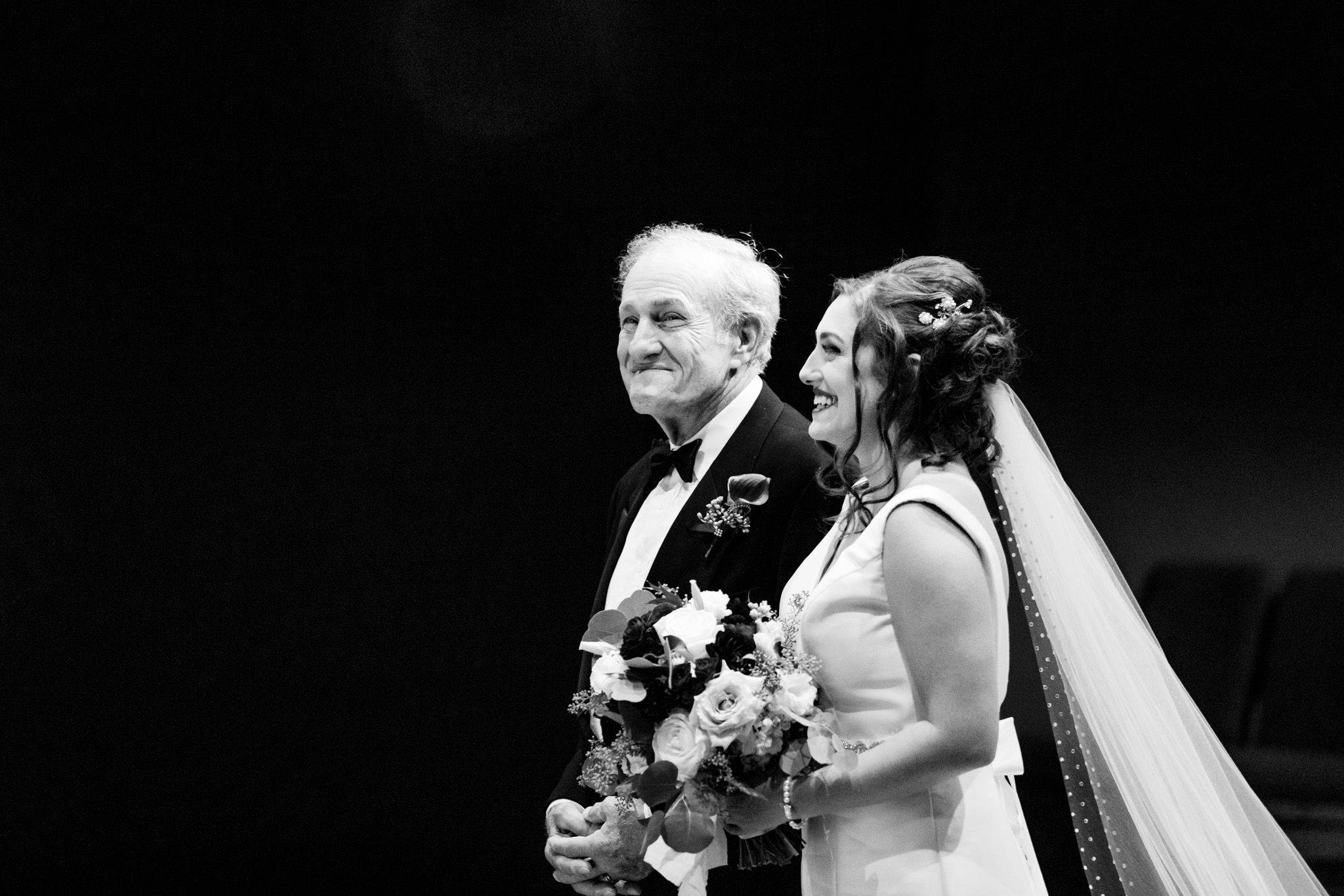 black and white photo of bride walking down aisle with her father