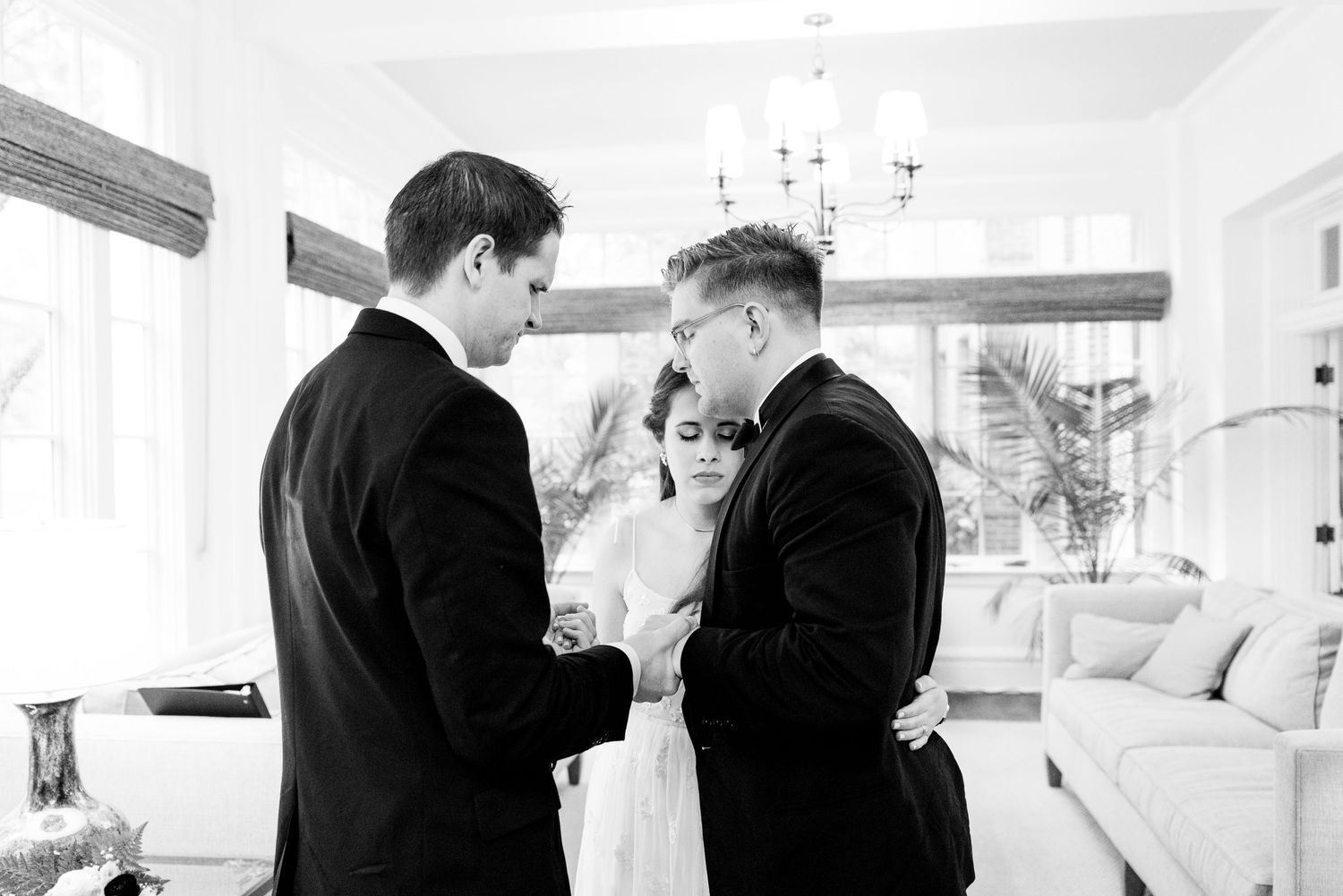 bride hugs groom with eyes closed as pastor prays over them before their wedding day