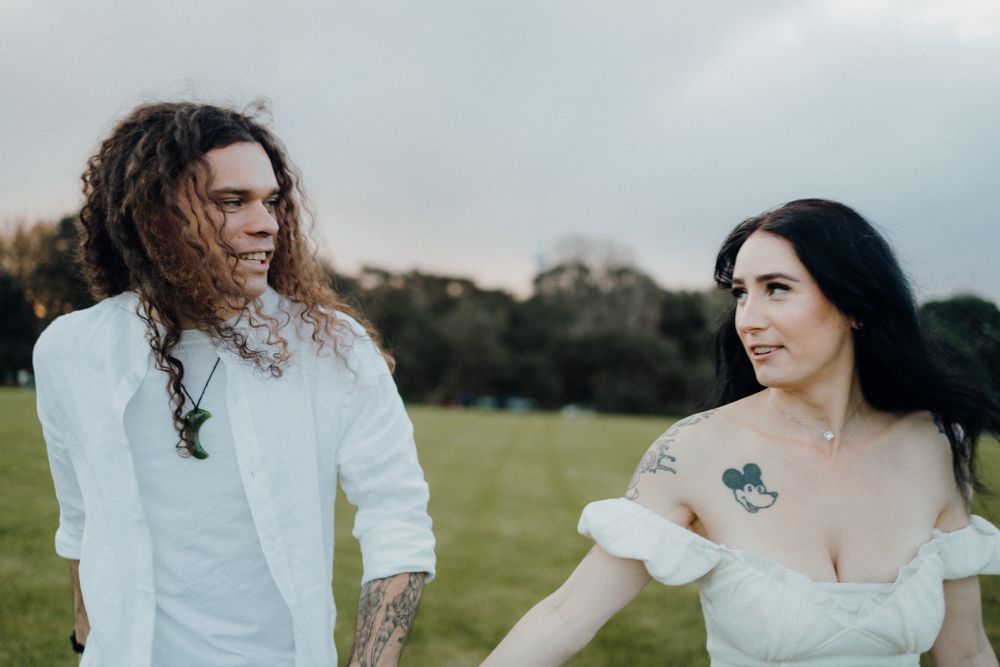 Couple in white outfits sharing a romantic moment in a sunny field.
