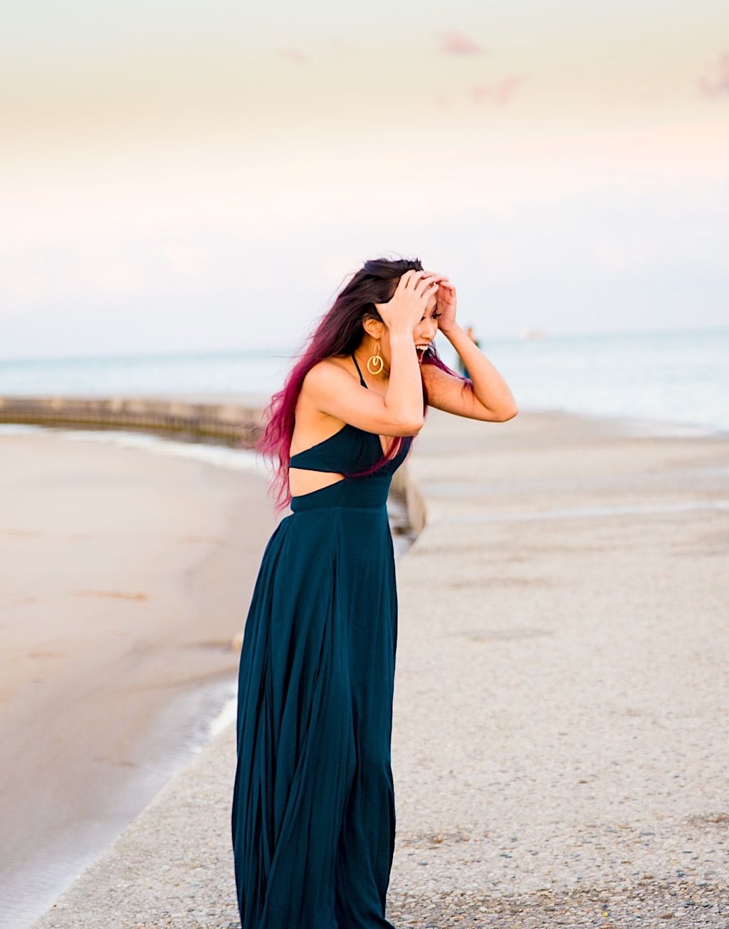 woman in teal dress with long pink hair has hands on face and looks surprised
