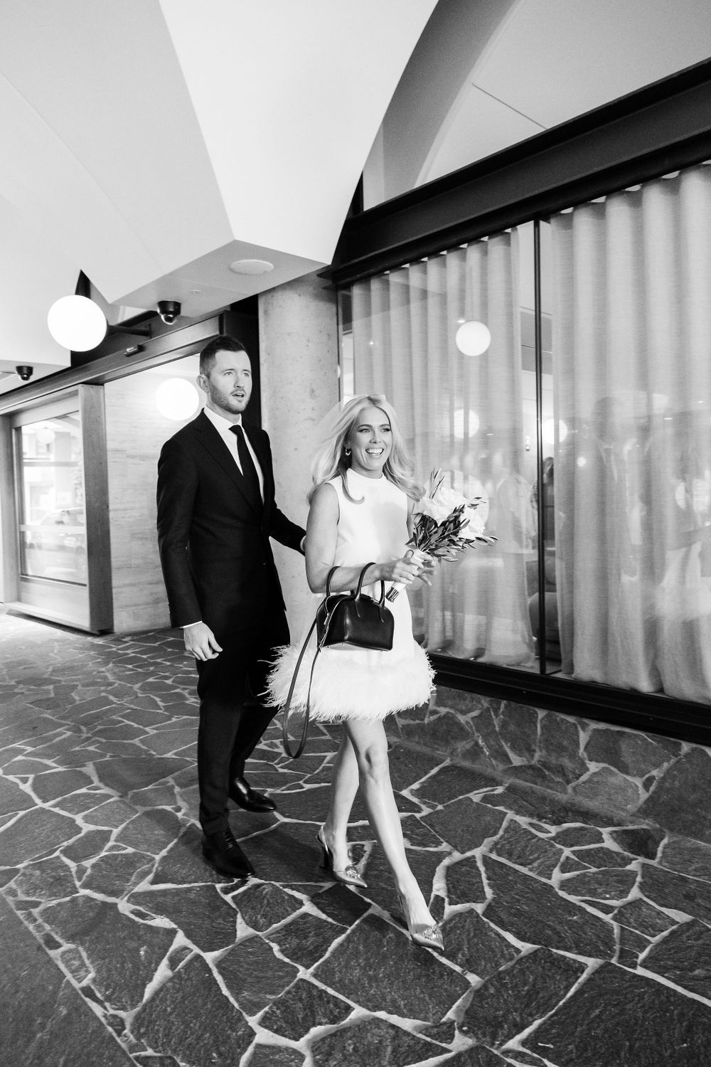 Wedding couple walks through modern venue with geometric floor patterns.