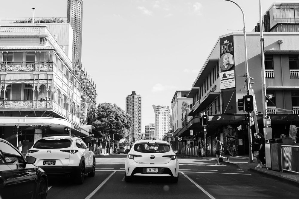 Black and white urban street scene in Brisbane with cars and buildings.