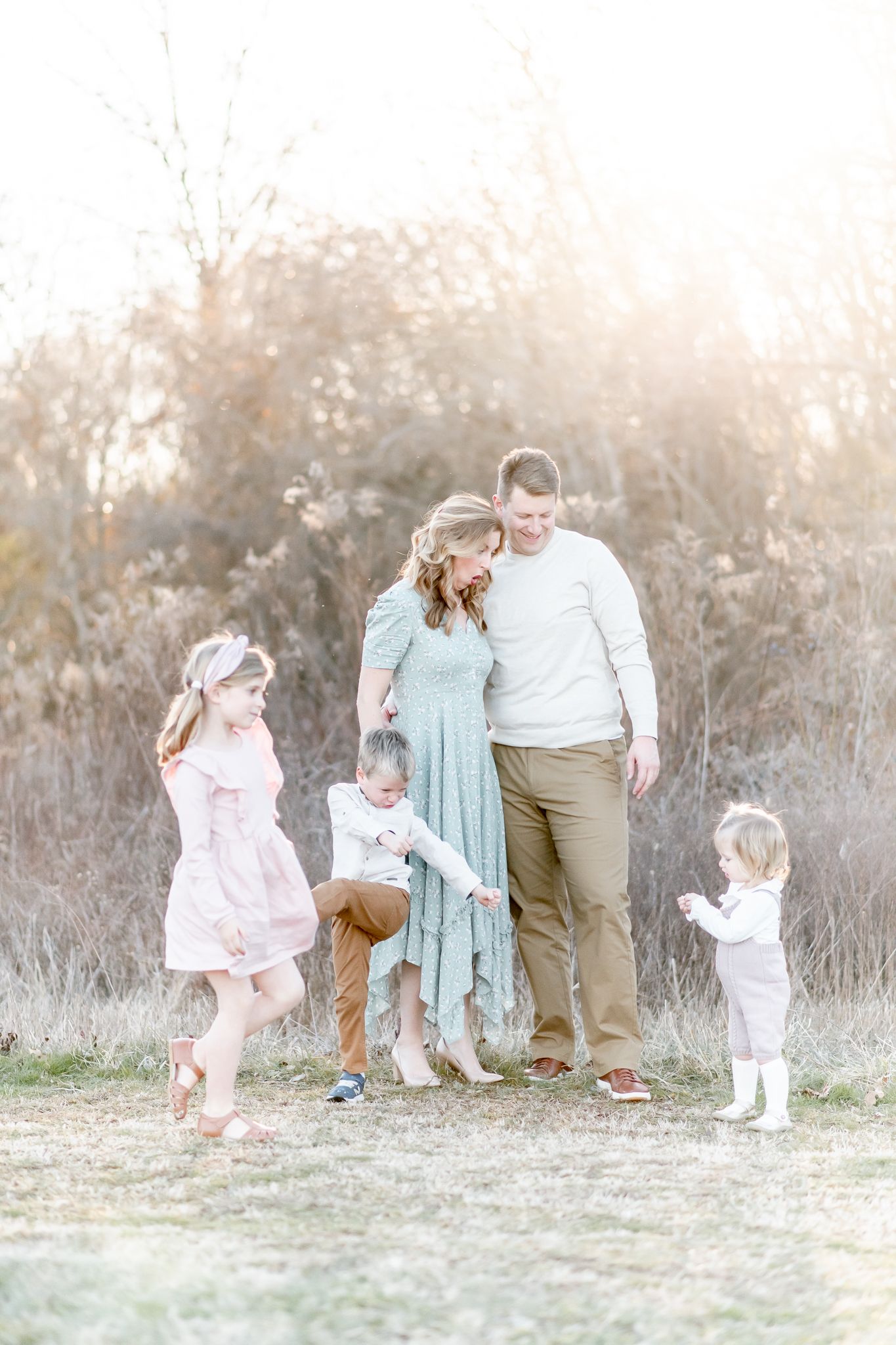 Children dance around their parents standing in a field