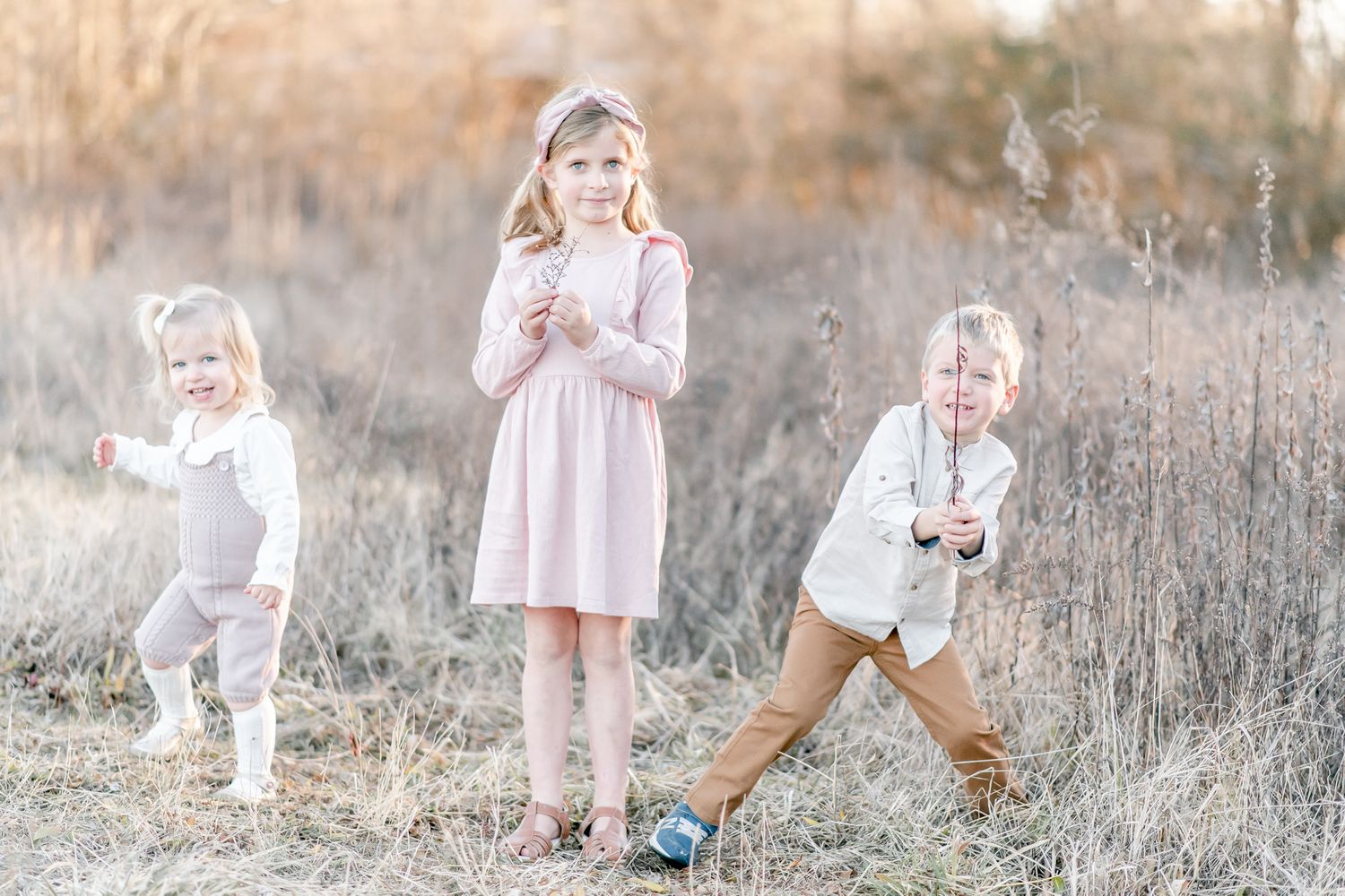 Siblings play in a field at sunset
