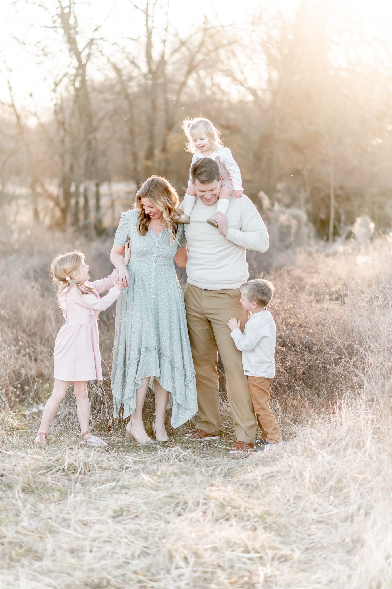 Family of 5 pose in a field with toddler on dad's shoulders