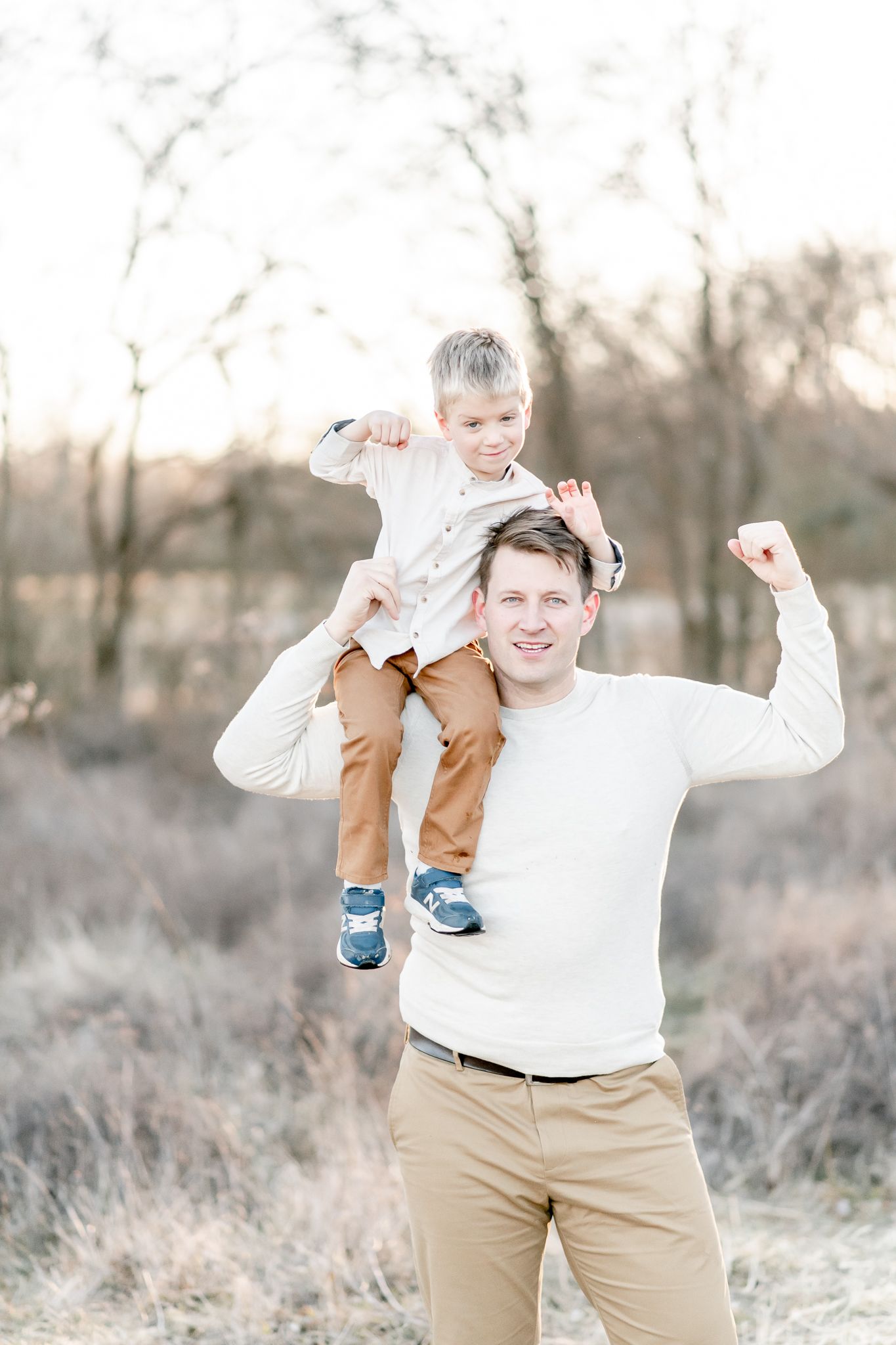 Father holds son on shoulders and flexes their muscles