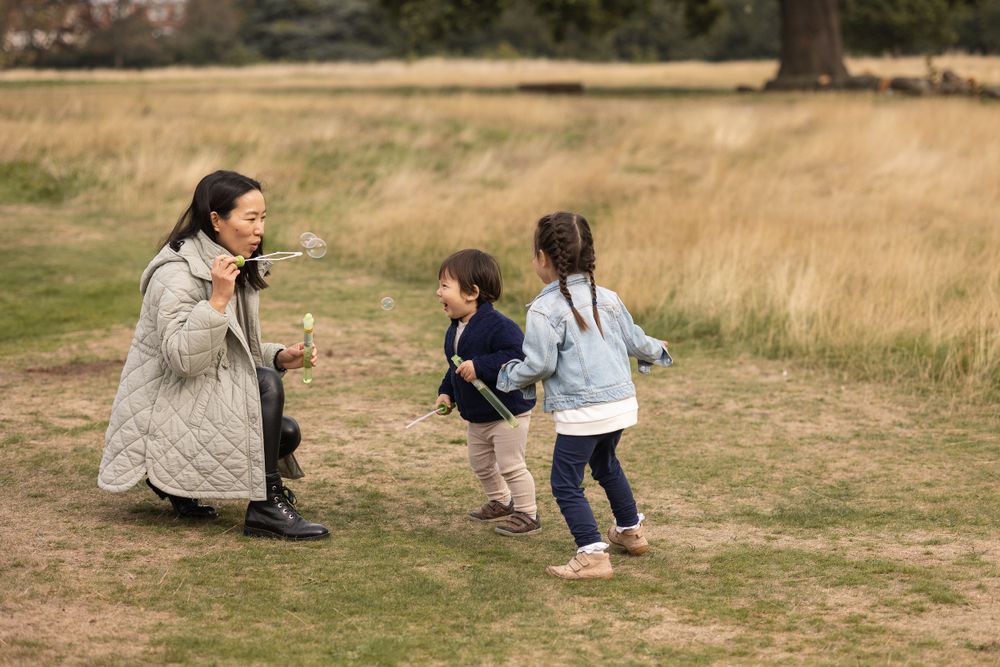 Young family blowing bubbles in Grovelands park