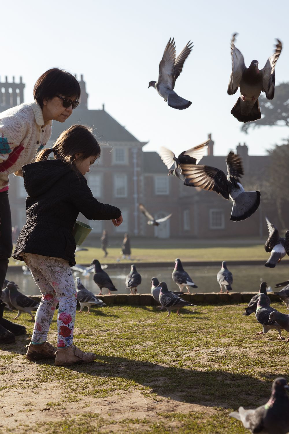 Grandmother and granddaughter feeding birds outside Forty Hall Estate